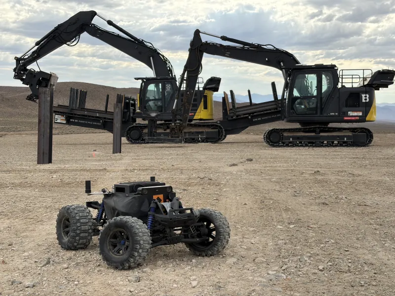The 1/5-scale survey robot on a Nevada solar site in front of two Built Robotics robotic pile drivers