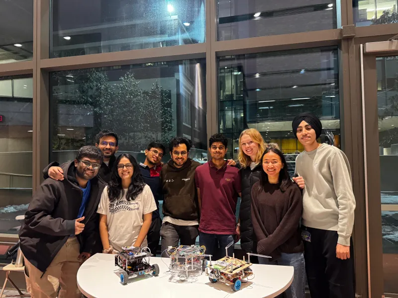 Group photo of the mechatronics class behind three small mobile robots